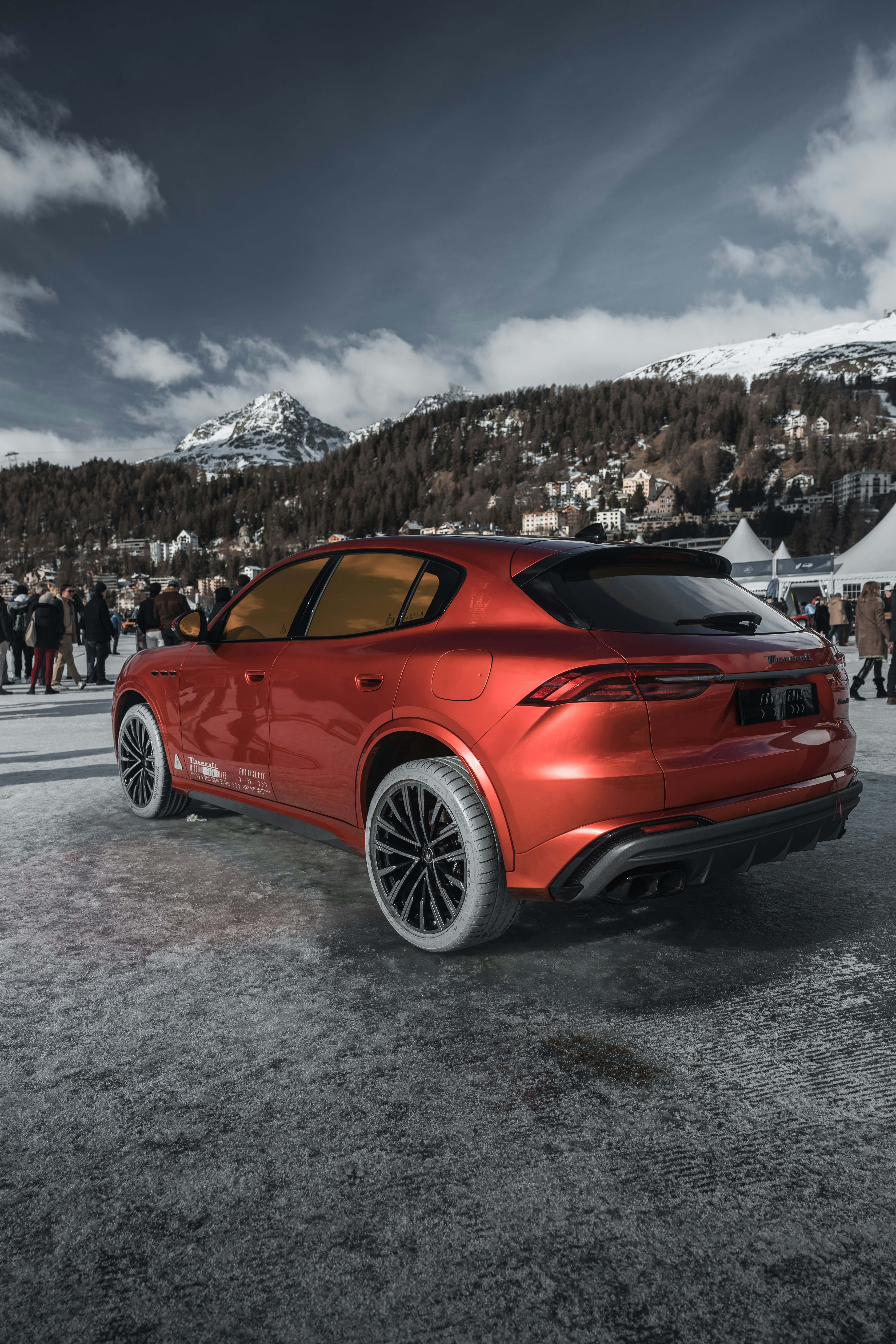 A red car parked in front of a crowd of people