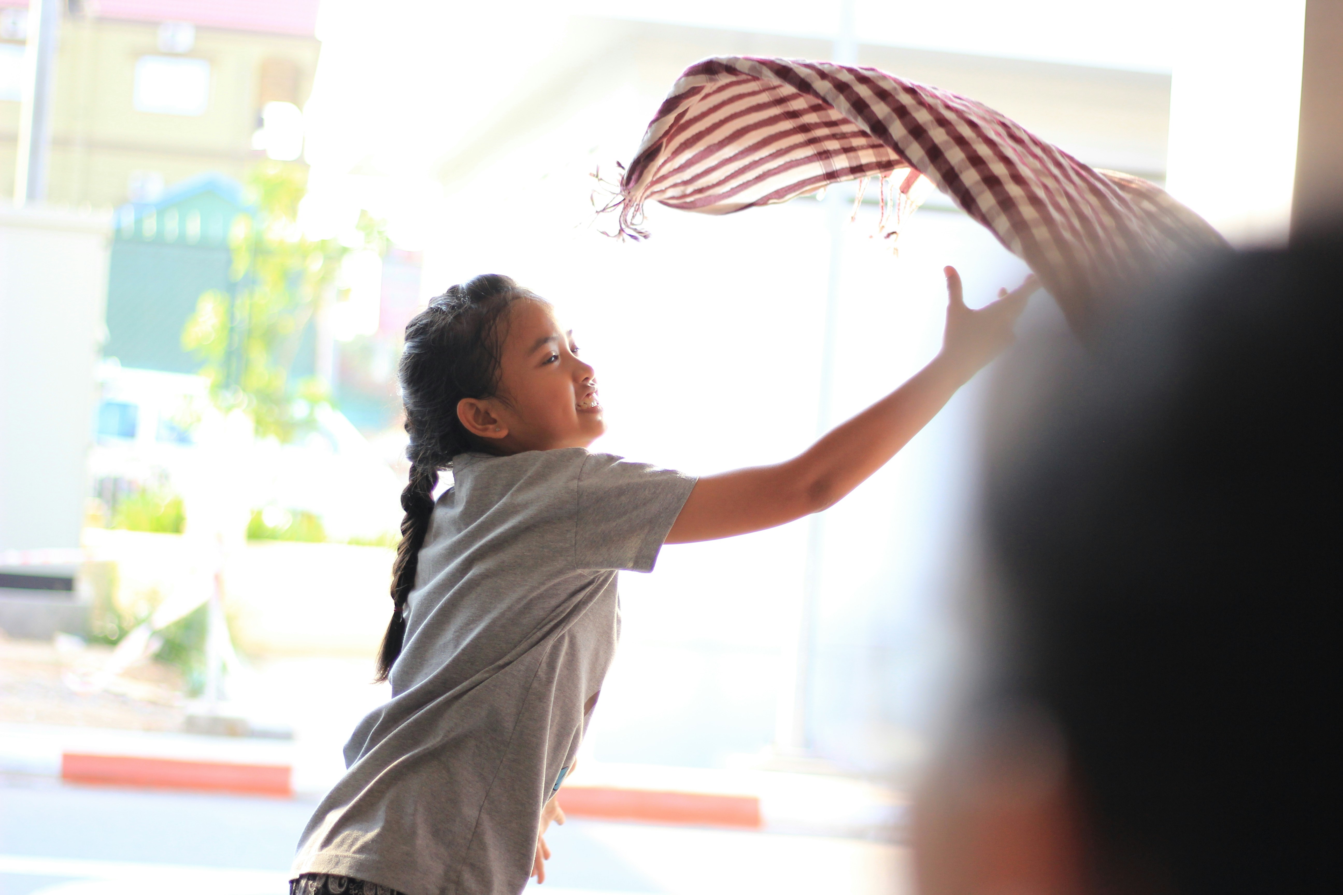 A young girl holding an american flag in front of a window