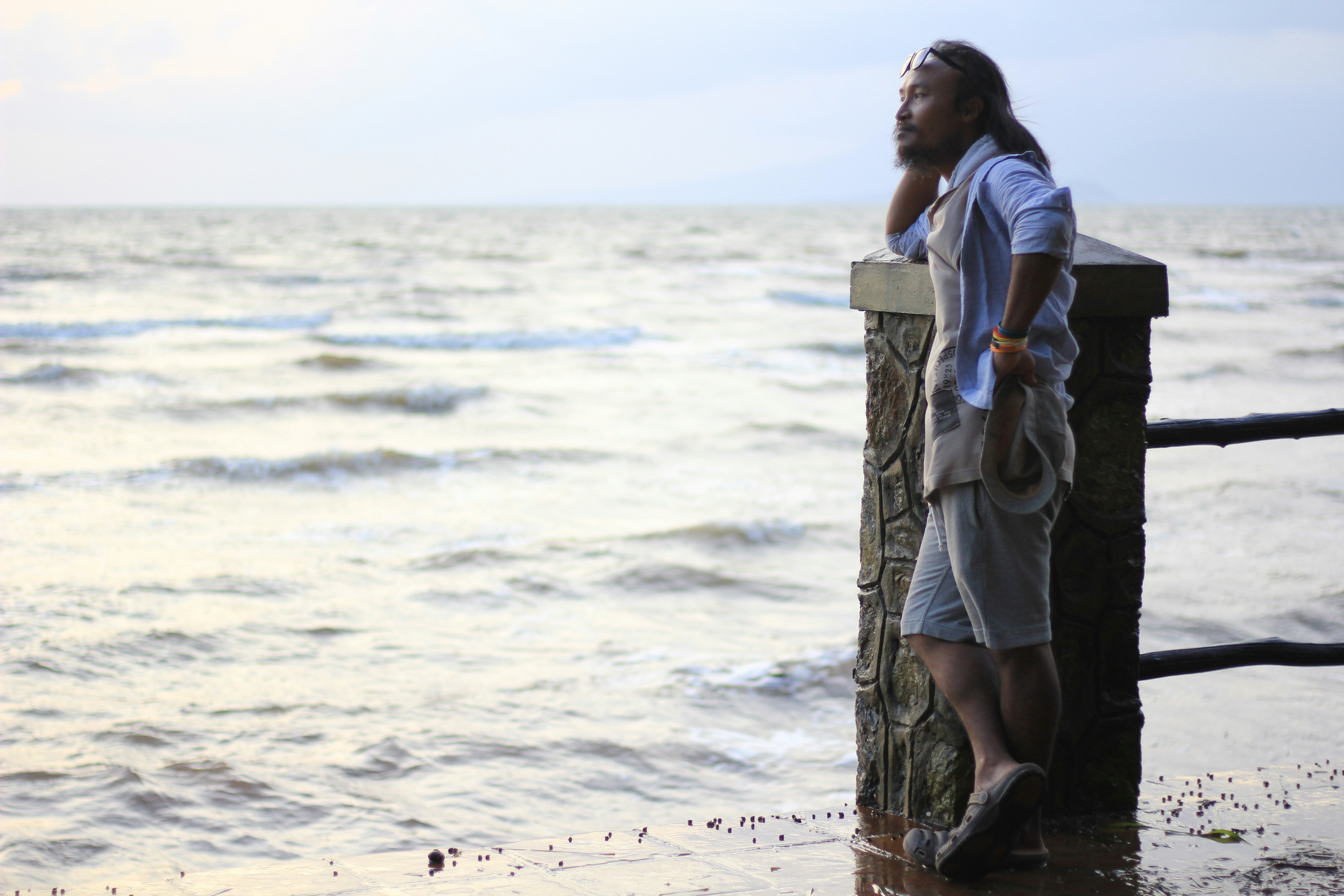 A woman standing on a pier next to the ocean