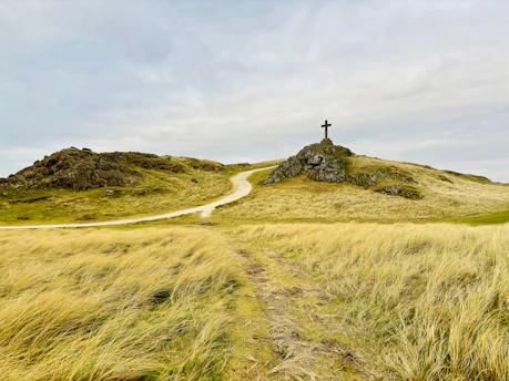 A grassy hill with a cross on top of it. Hebrews 11:1 