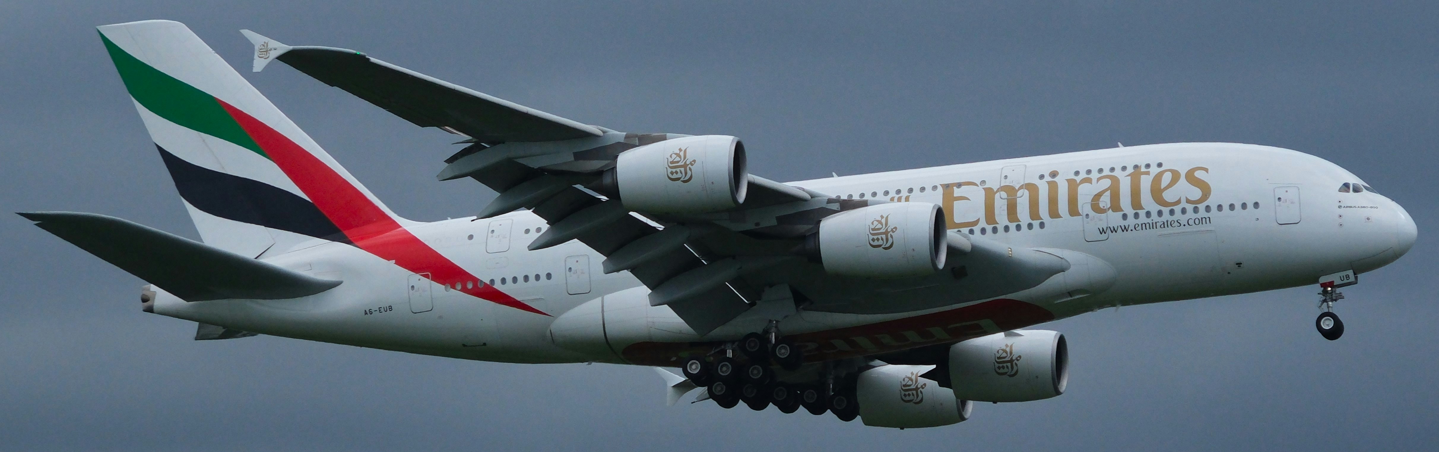 A large jetliner flying through a cloudy sky, Emirates Airbus A380 landing at LHR