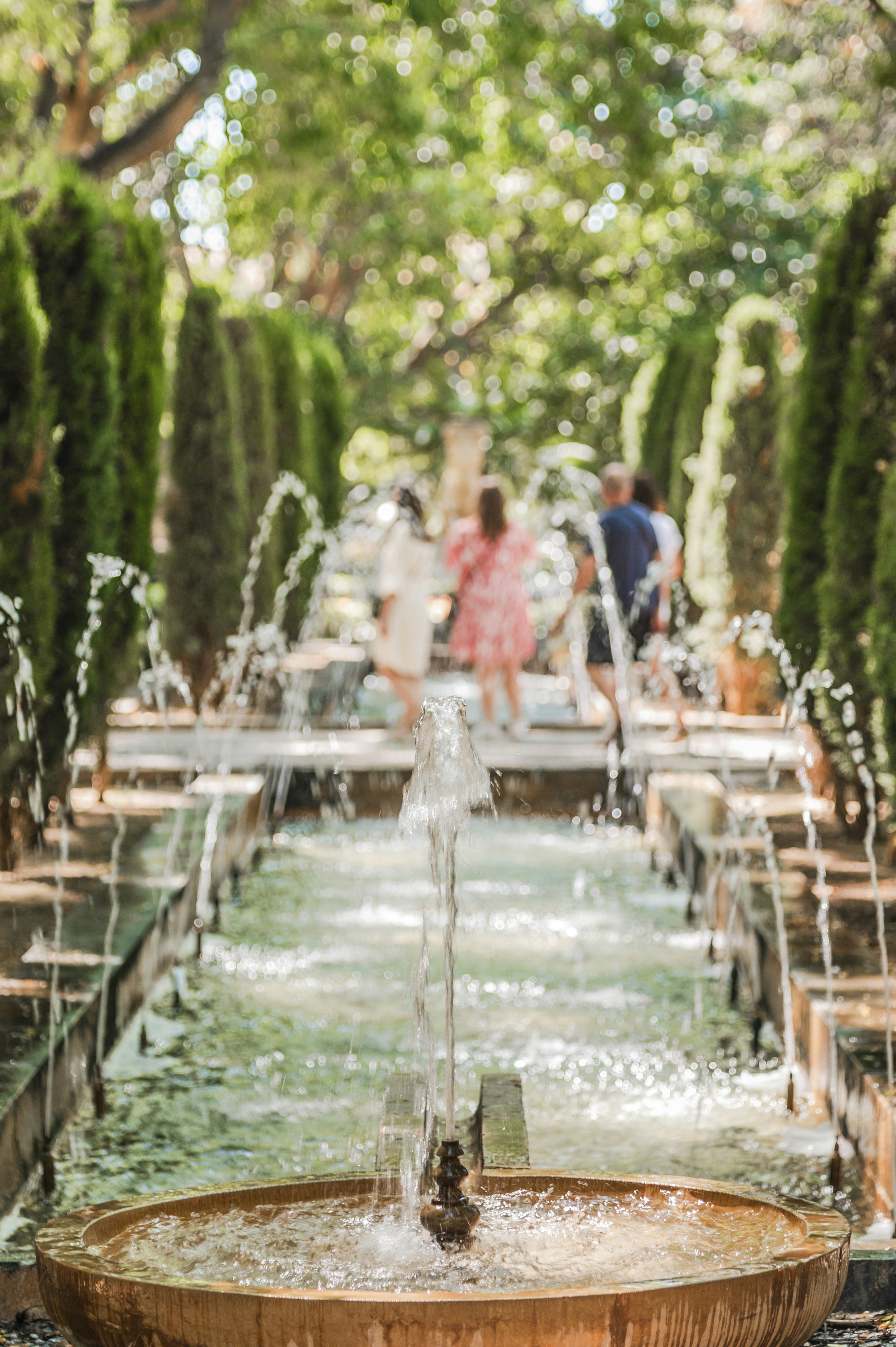 A water fountain with people walking around it