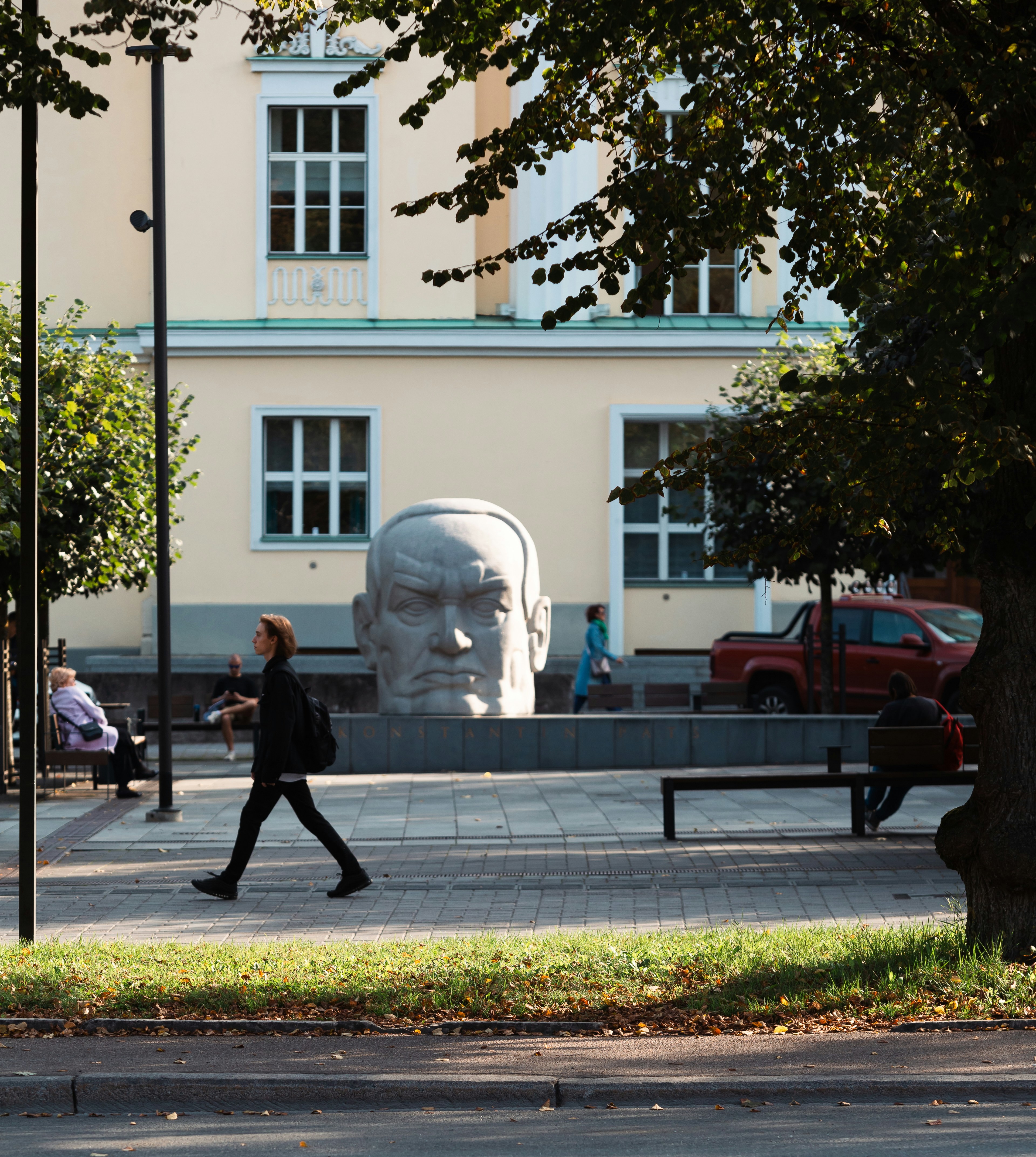A woman walking past a statue in a park
