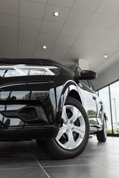 A black car is parked in a showroom