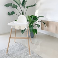 A white chair sitting next to a plant in a room