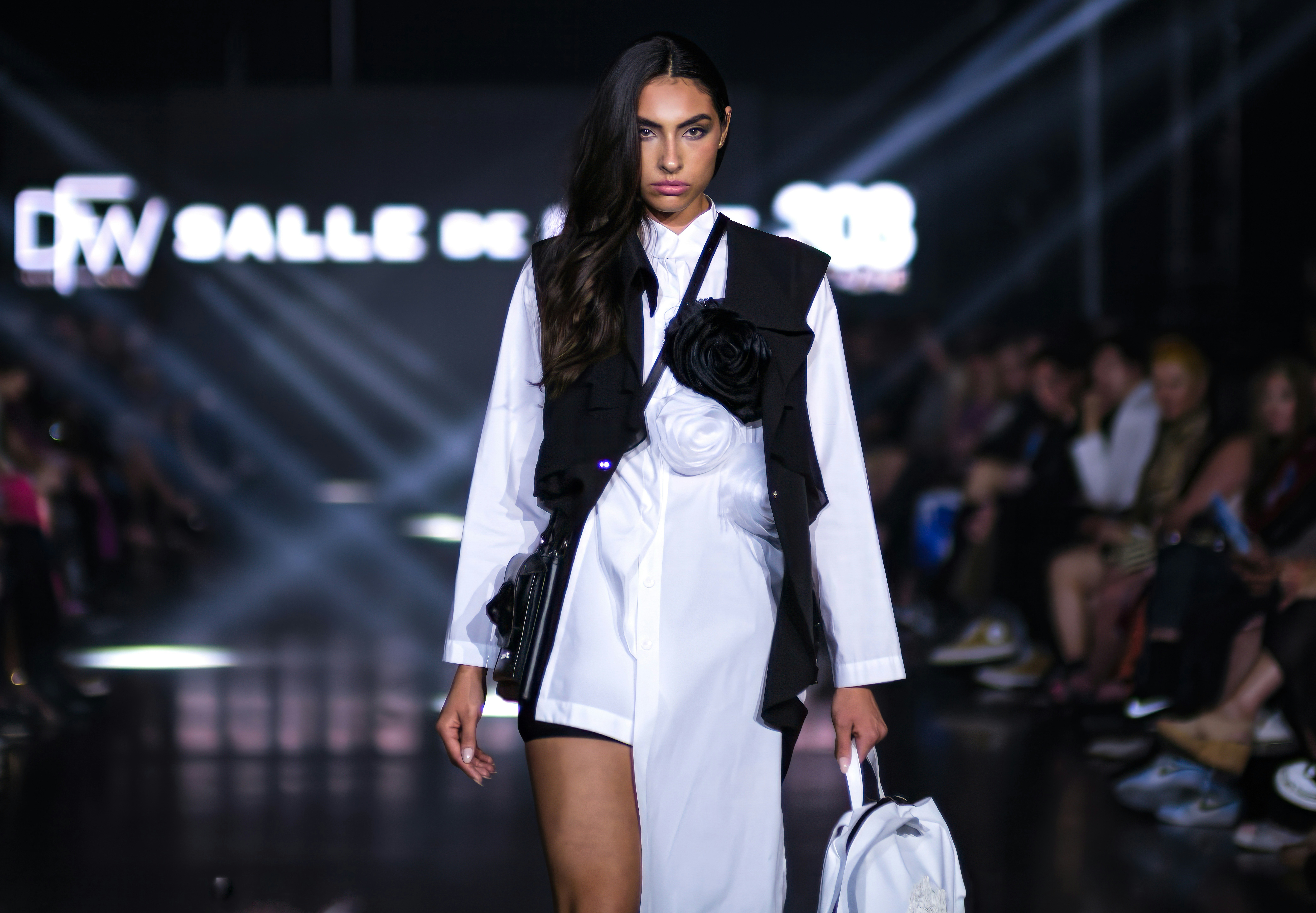 A woman walking down a runway with a handbag