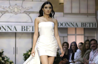 A woman in a white dress walking down a runway