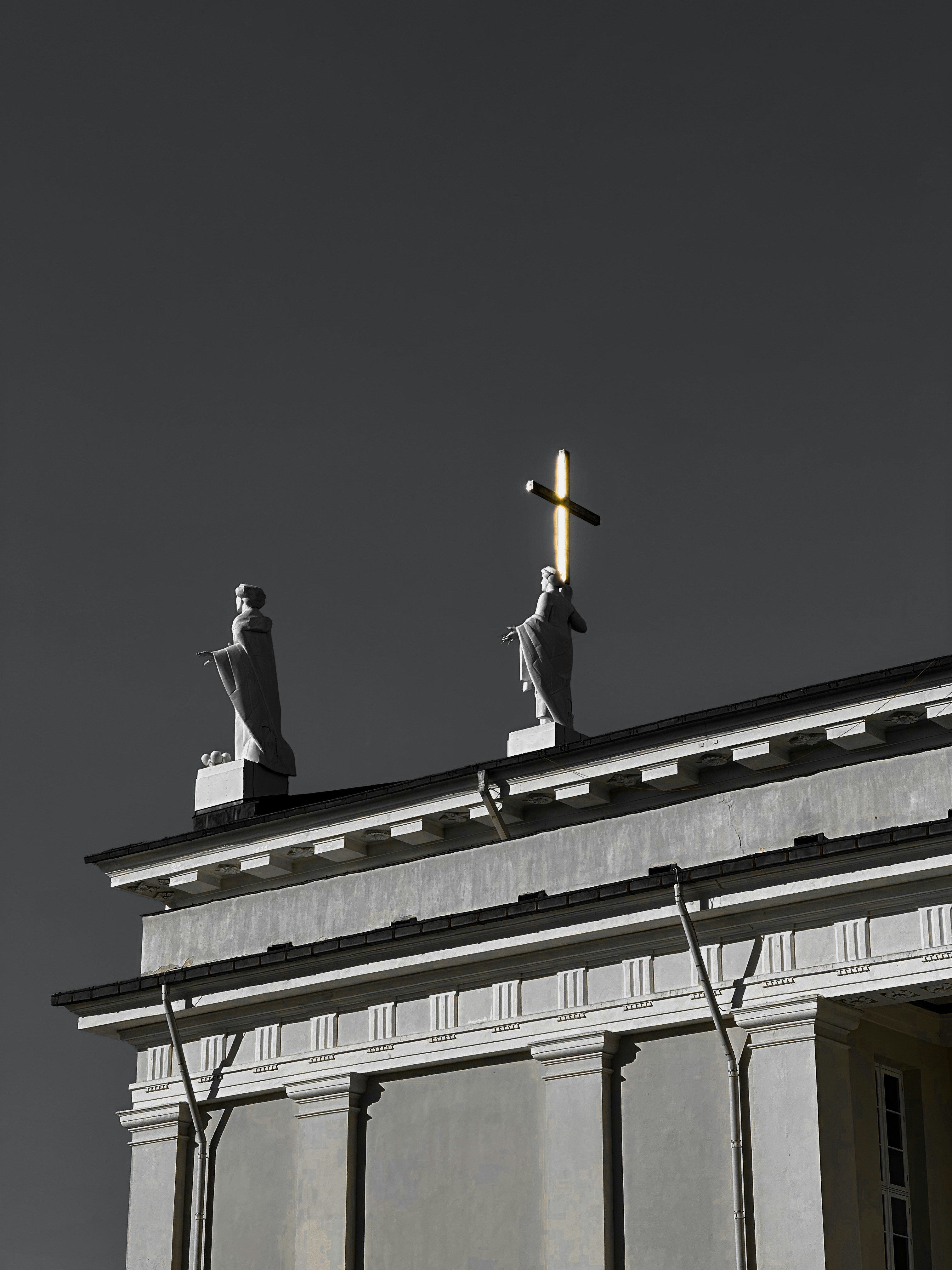Two statues on top of a building with a sky background