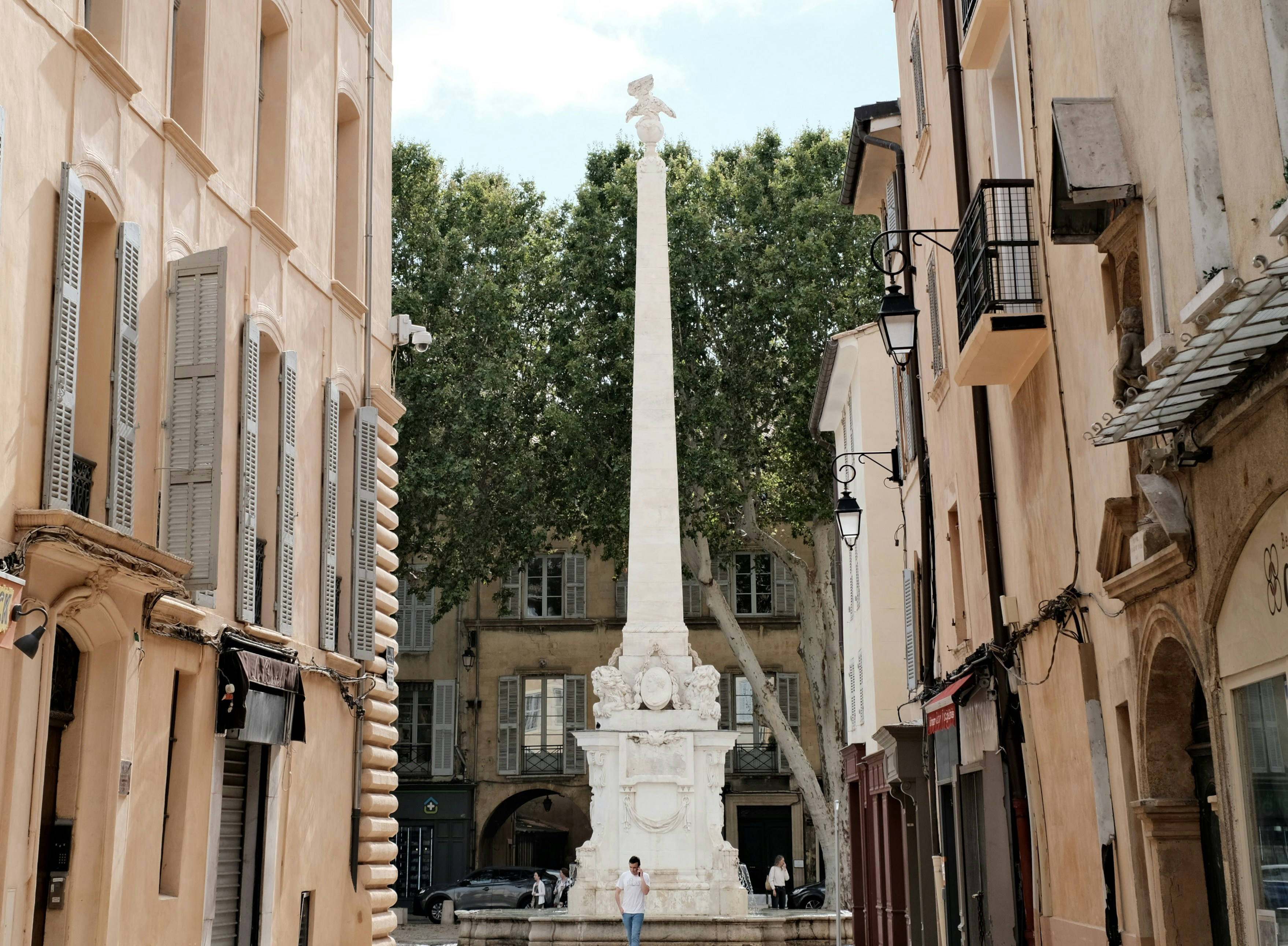 A narrow city street with a monument in the middle