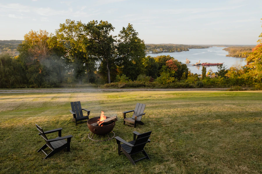 Chairs around a fire pit on a lawn above a river