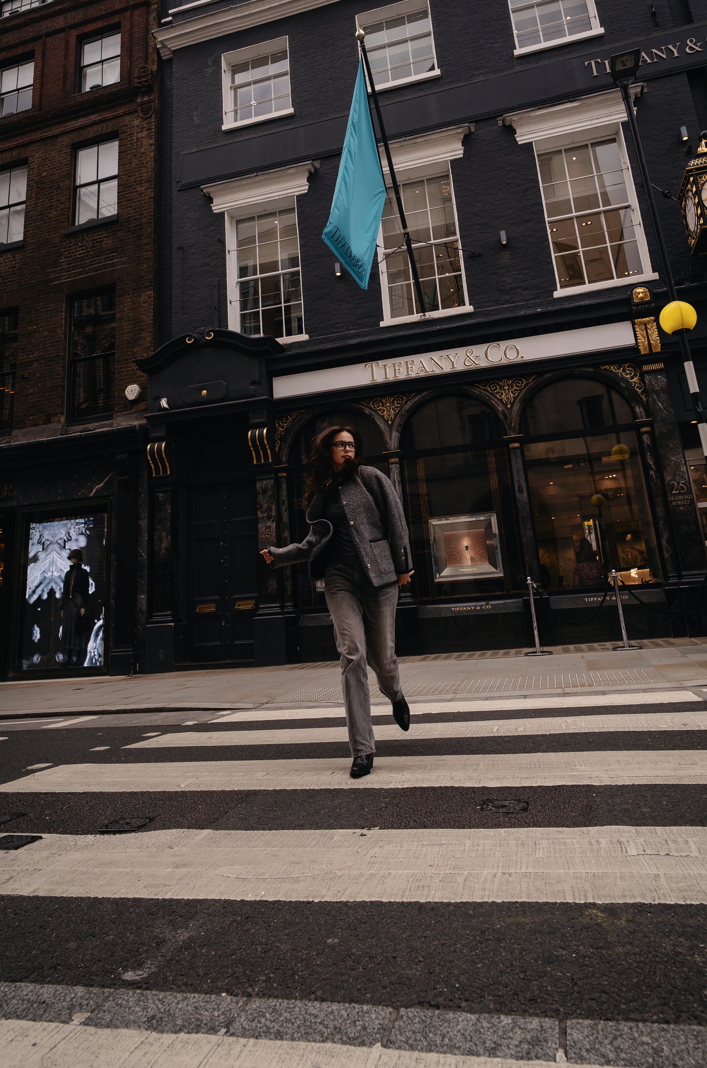 A woman crossing the street in front of a building