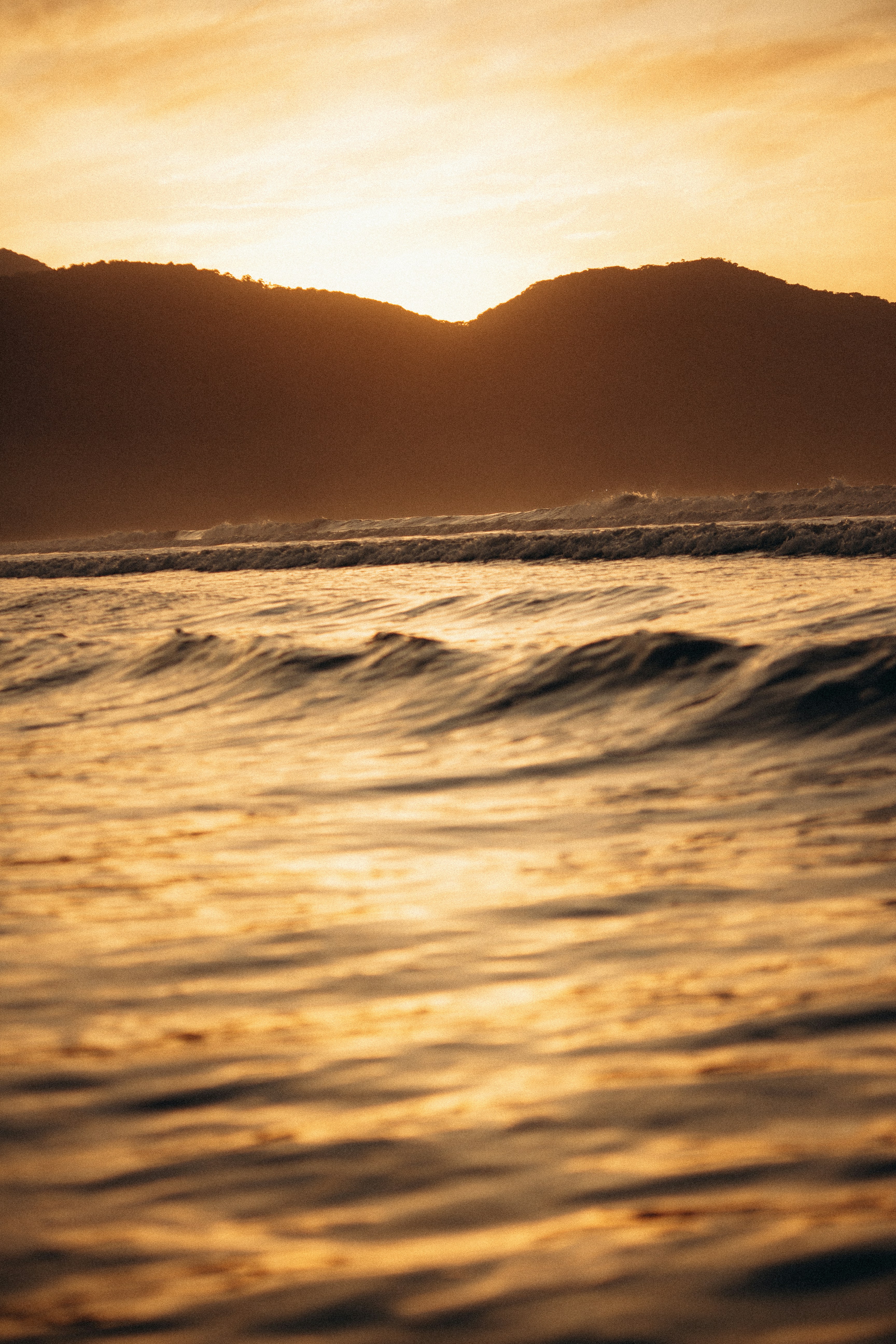 O sol está se pondo sobre o oceano com montanhas ao fundo
