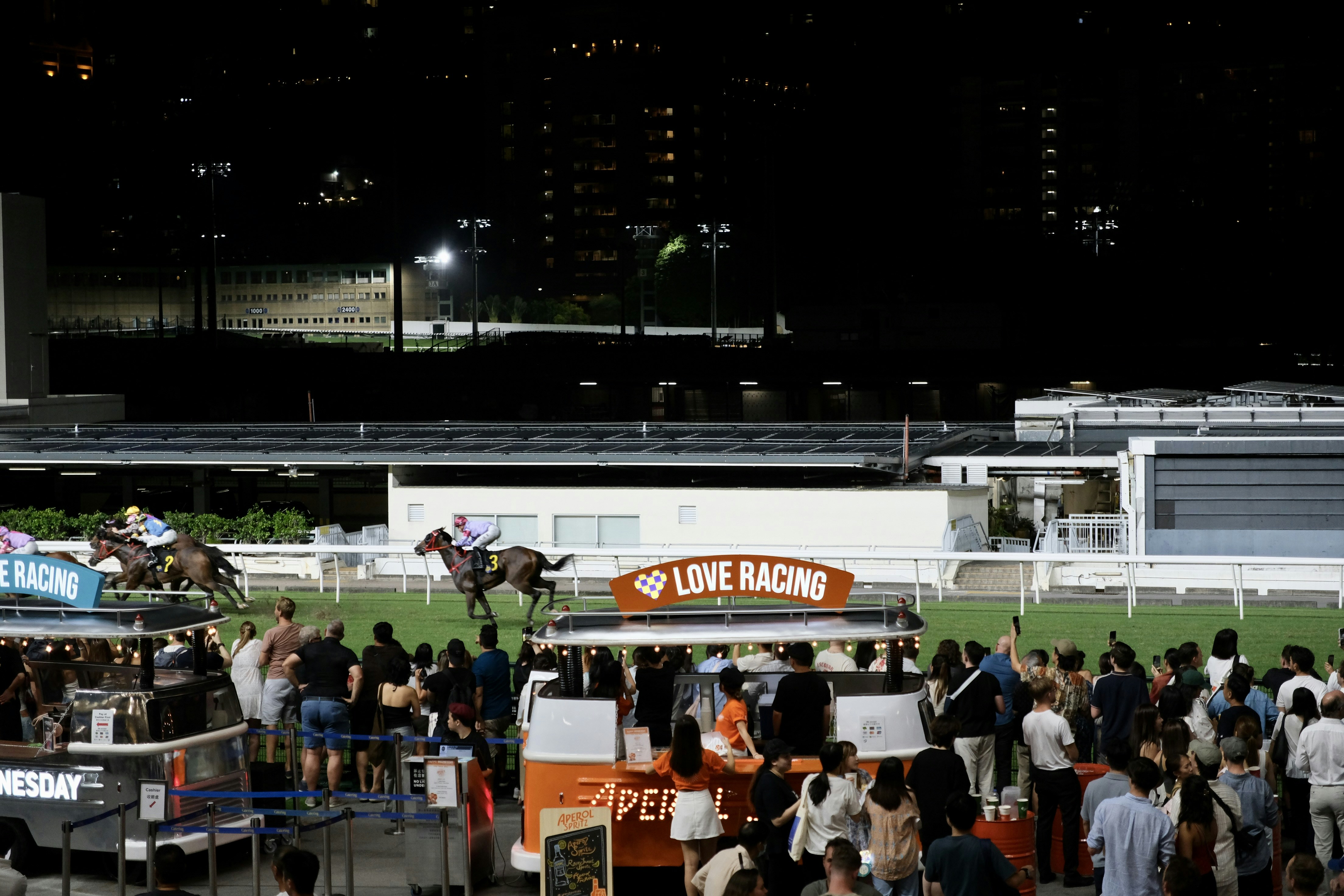 A crowd of people standing around a horse race track