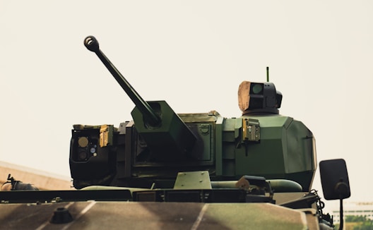 A military tank driving down a road next to a field