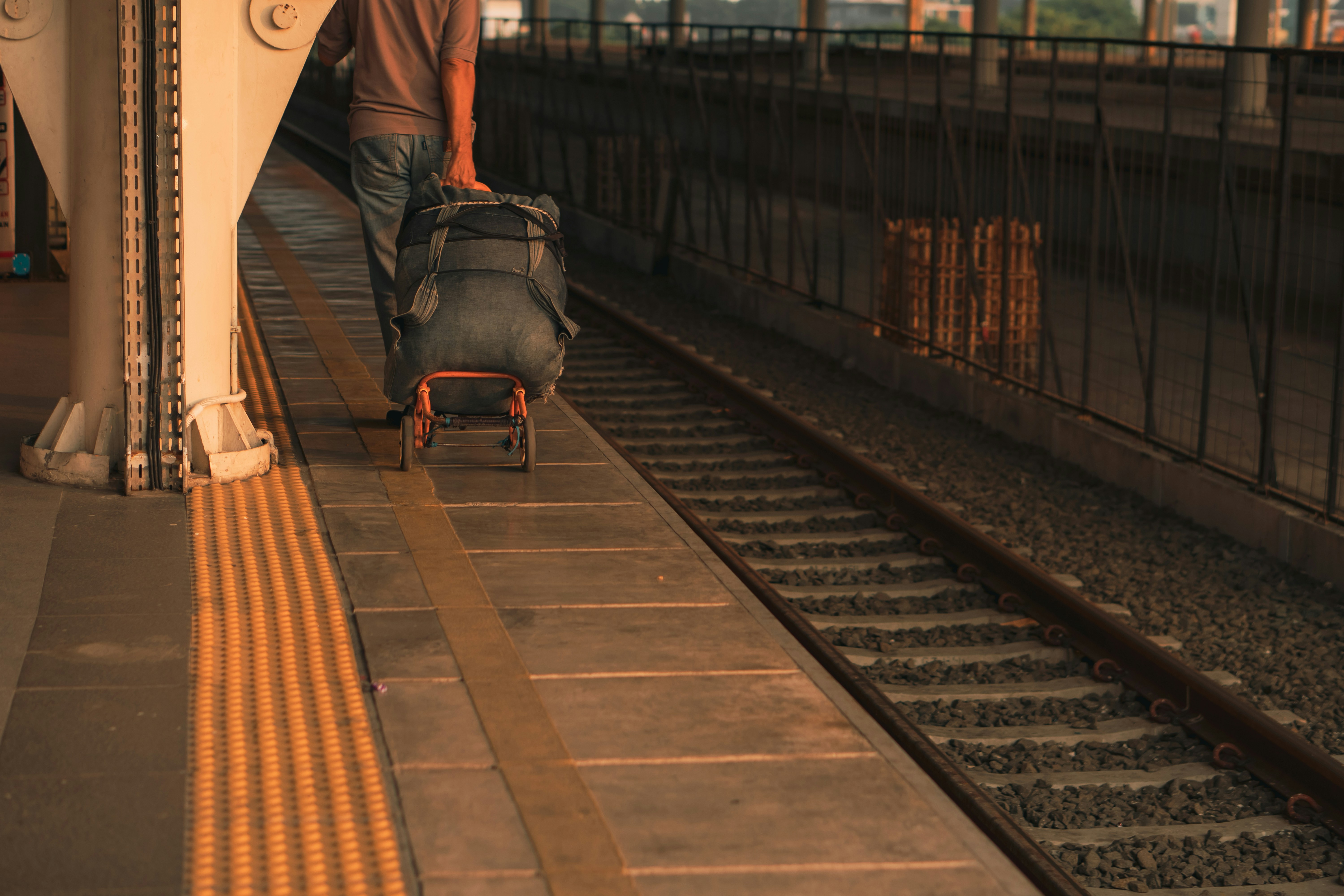 A man pulling a suitcase down a train track, 