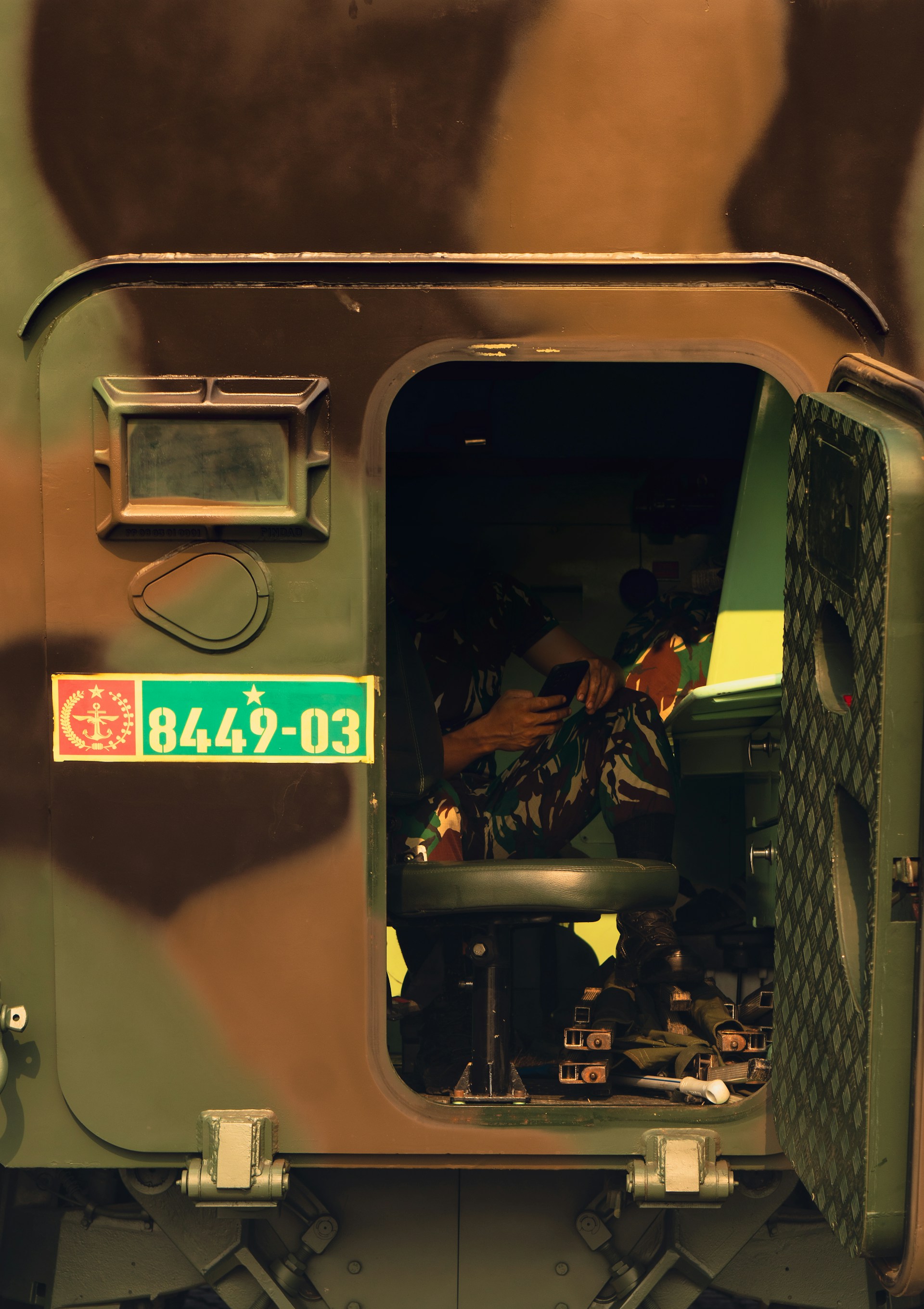 A soldier is sitting in the back of a military vehicle