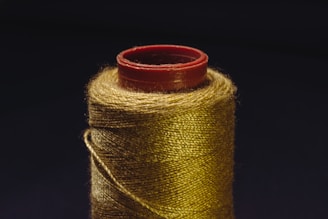 A spool of gold colored thread with a spool of red thread