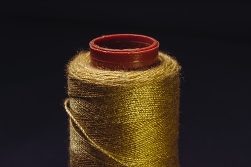 A spool of gold colored thread with a spool of red thread