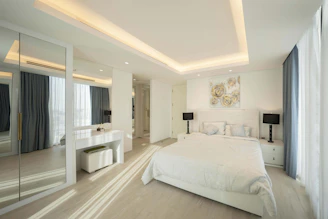 A bedroom with a large white bed sitting next to a window