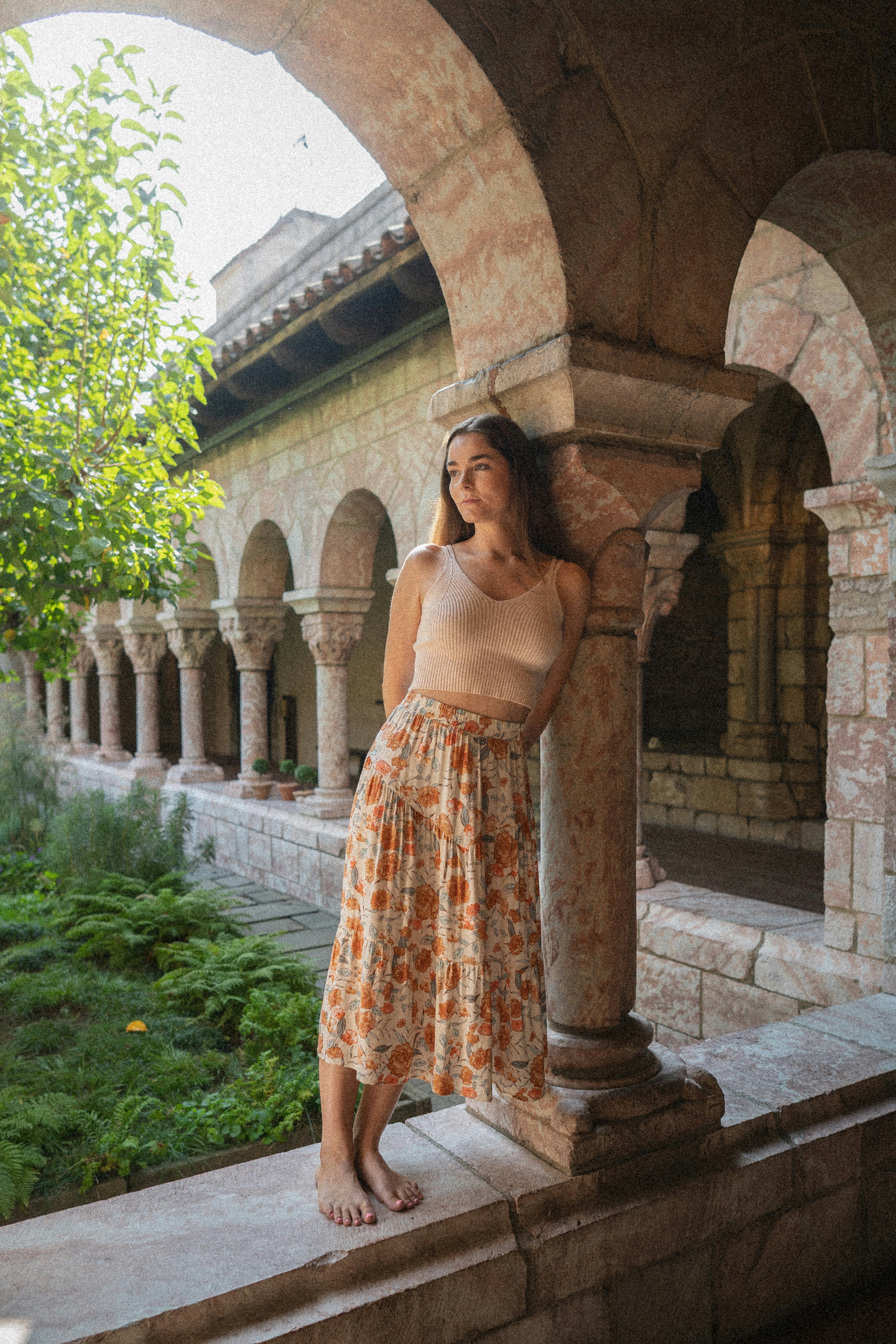 A woman leaning against a pillar in a courtyard