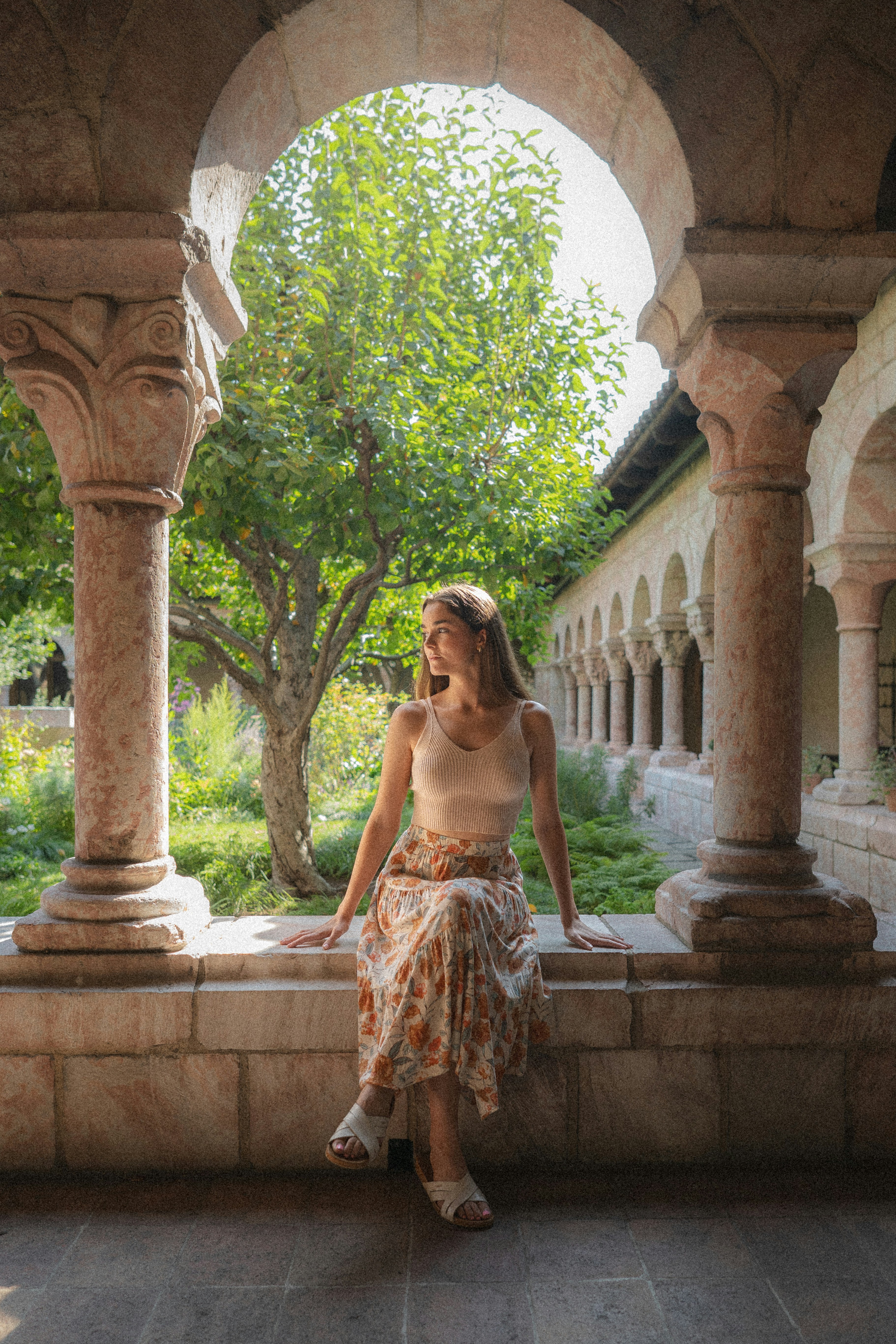 A woman sitting on a stone bench in a courtyard