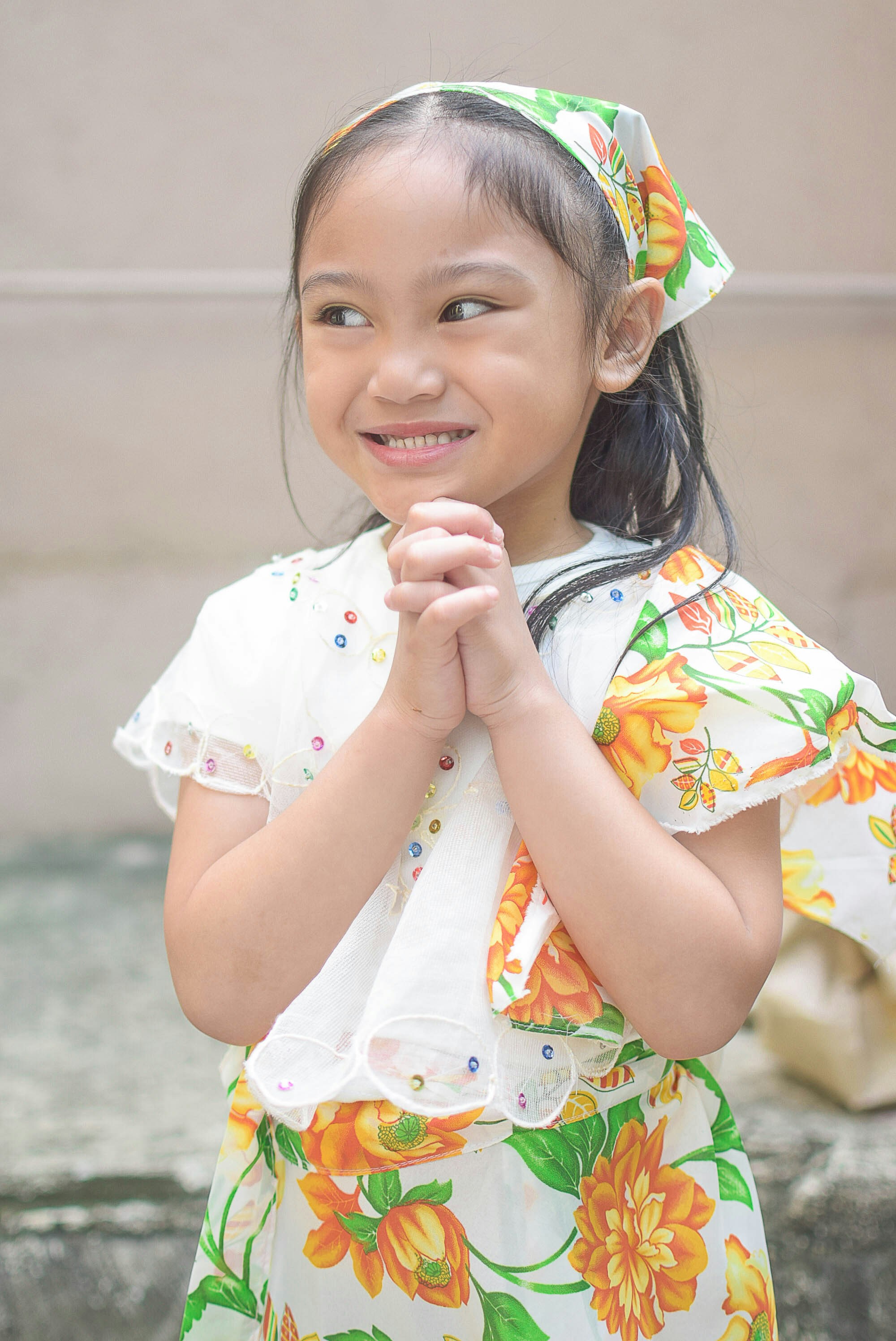 A little girl standing with her hands folded