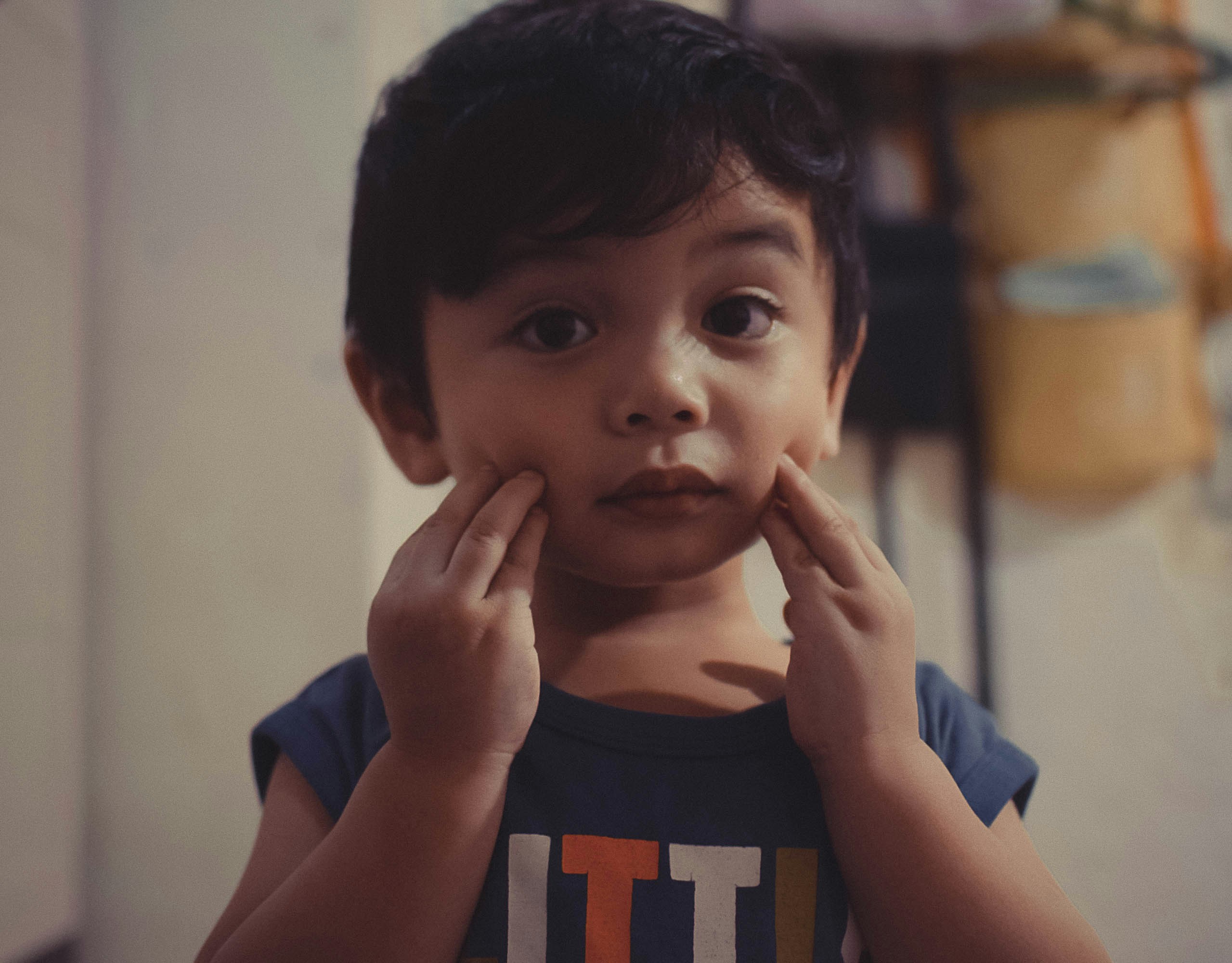 A young boy holding his hands to his face