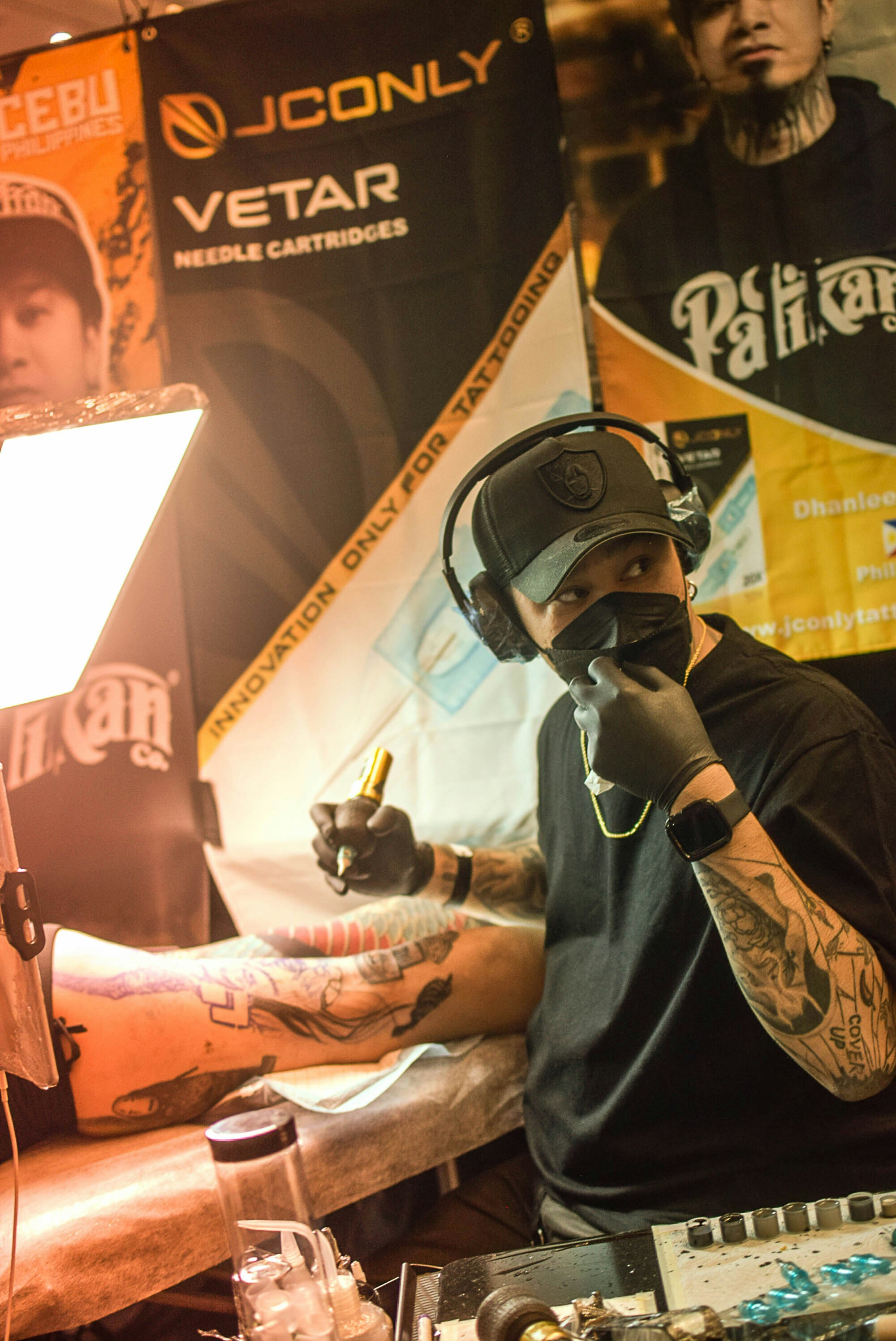 A man with a tattoo on his arm sitting in front of a microphone