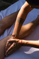 A person with a tattoo on their arm sitting on the ground