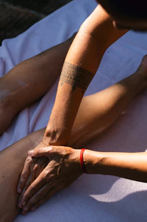 A person with a tattoo on their arm sitting on the ground