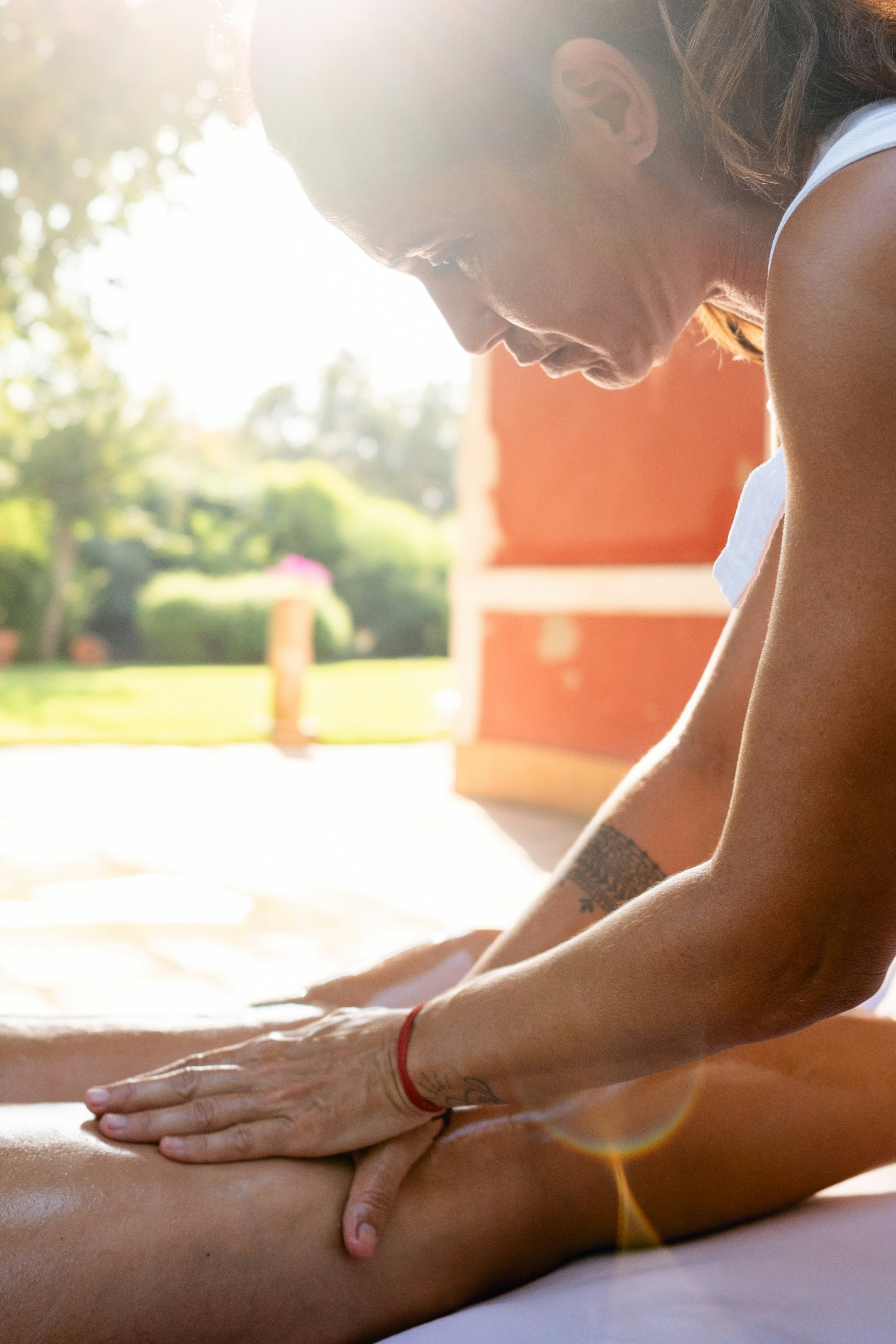 A woman in a white tank top is stretching her legs