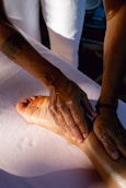 A person is doing a foot massage on a bed