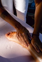 A person is doing a foot massage on a bed