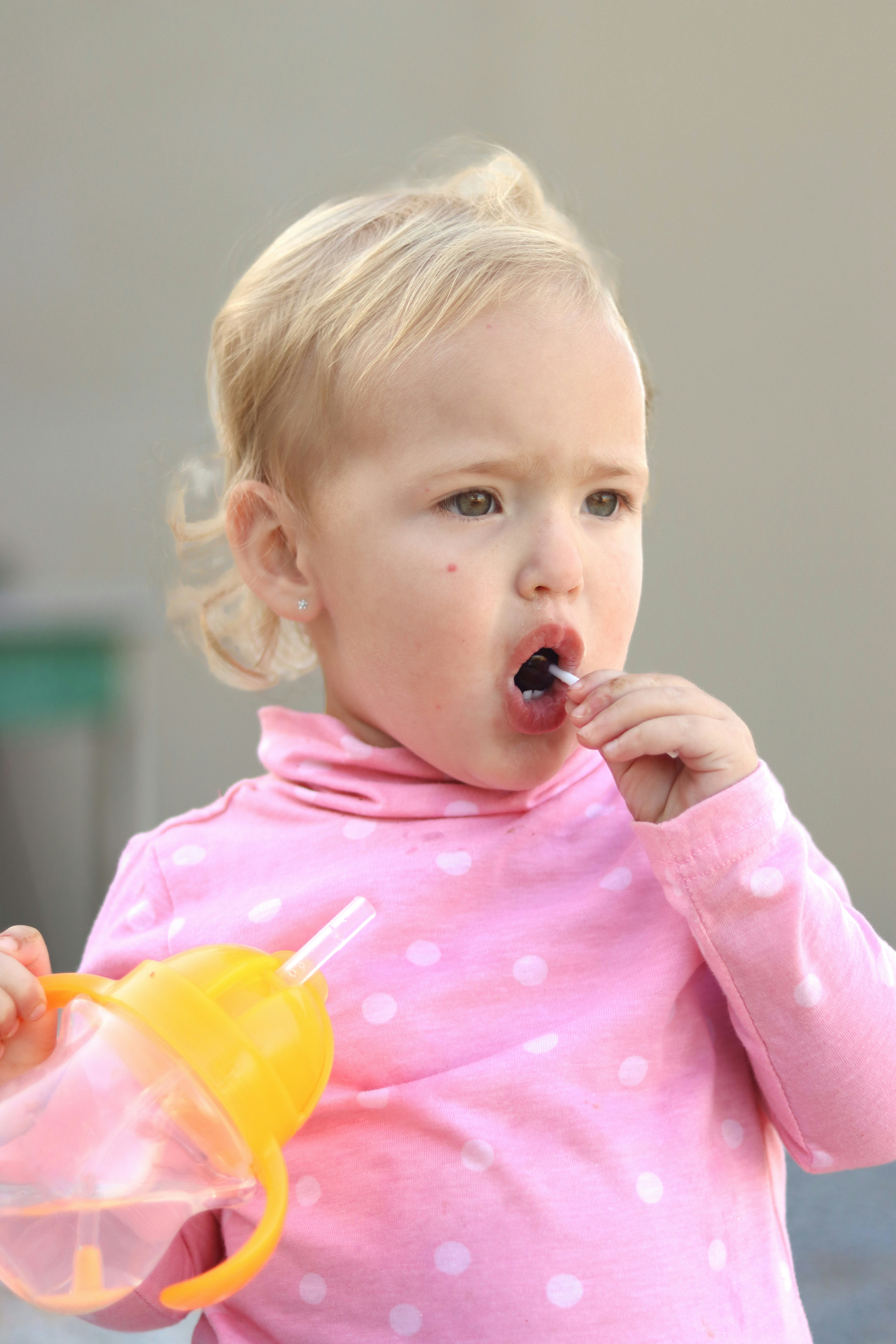 A little girl in a pink shirt brushing her teeth