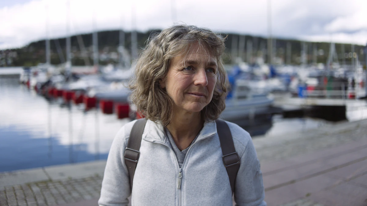 Femme souriante sur un port, sac à dos sur les épaules