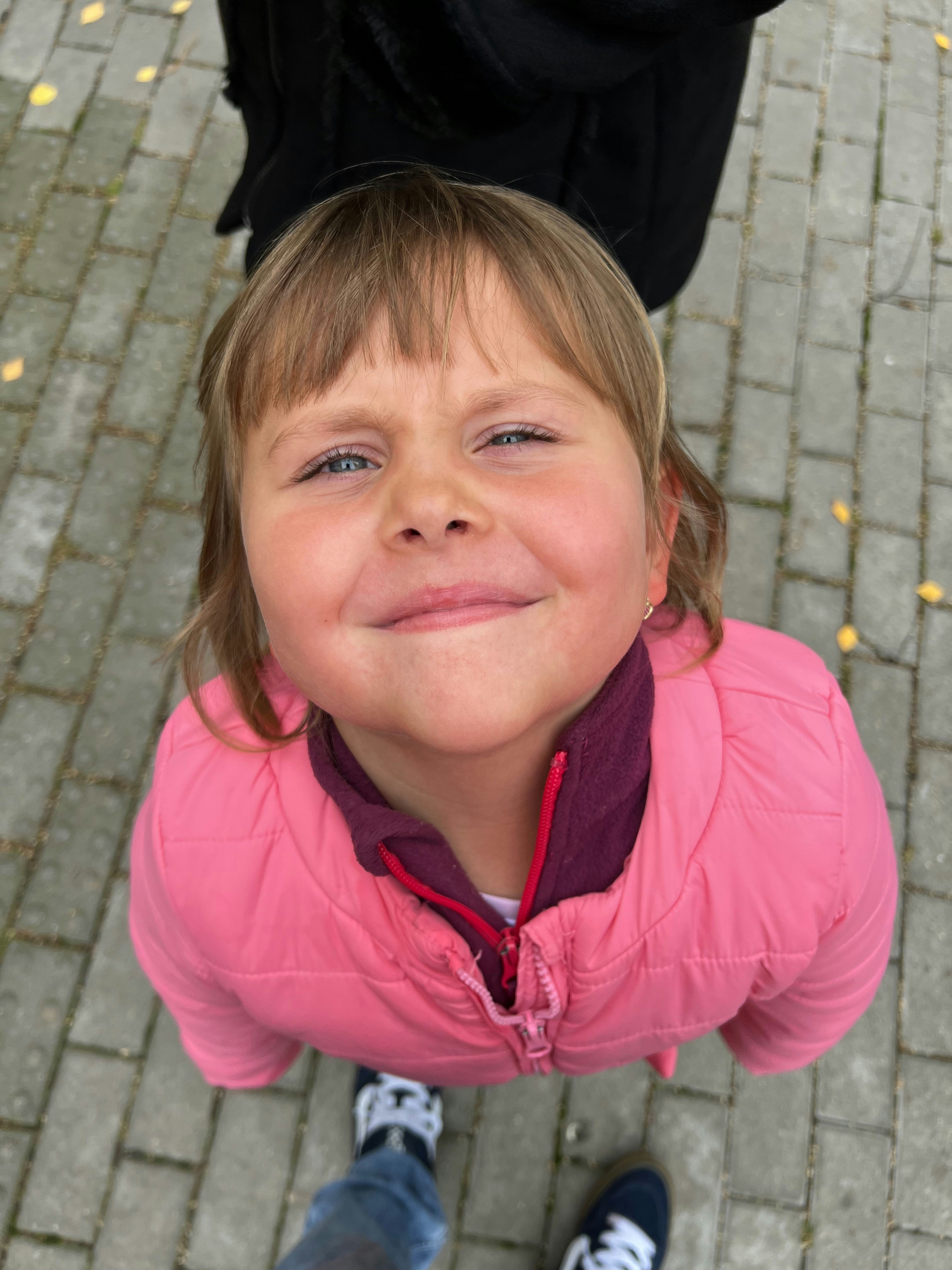 A little girl in a pink jacket standing on a sidewalk photo – Free ...