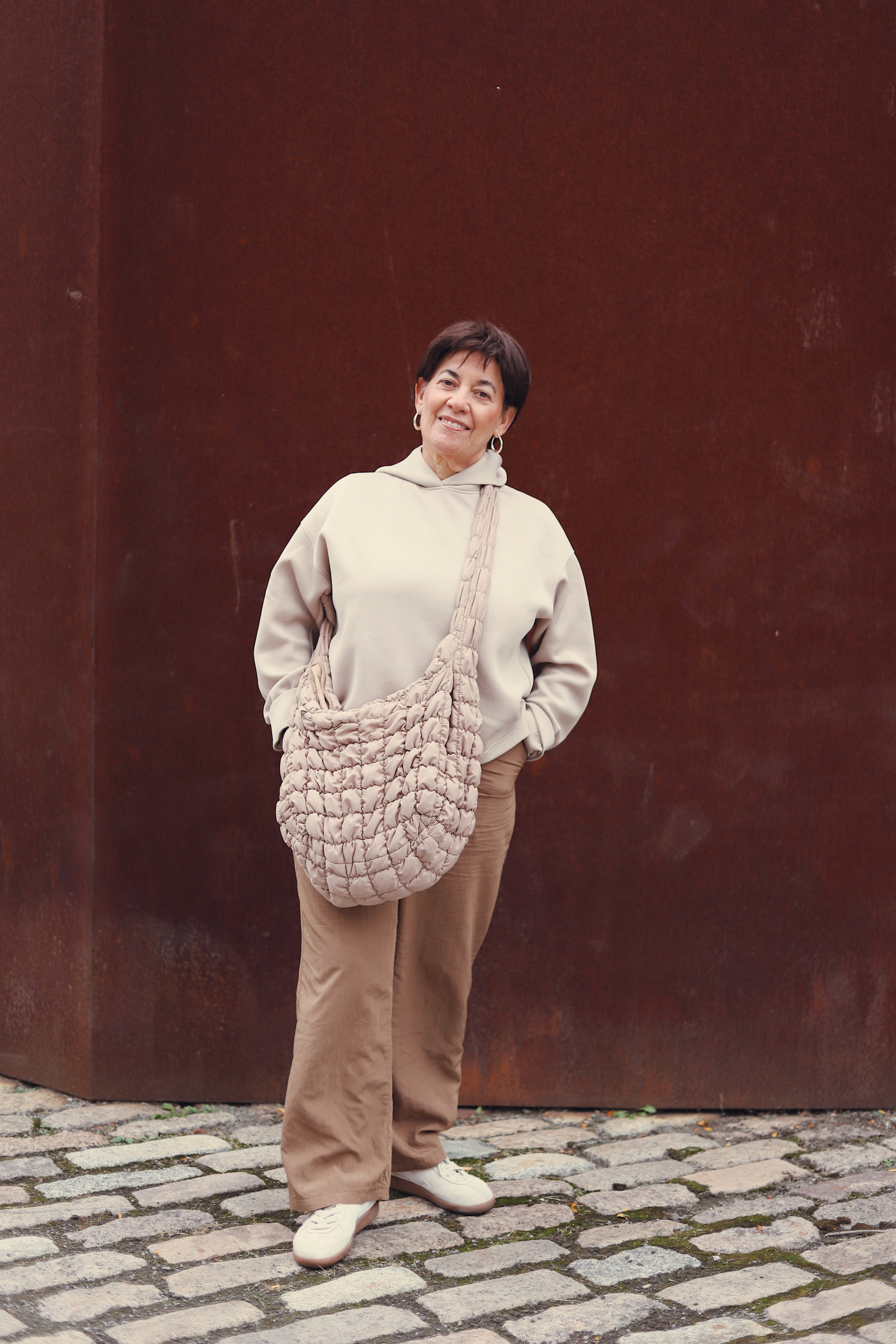 A woman standing in front of a brown wall