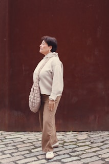 A woman standing in front of a brown wall