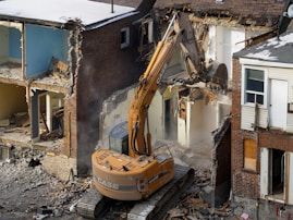 A bulldozer digging through the rubble of a building