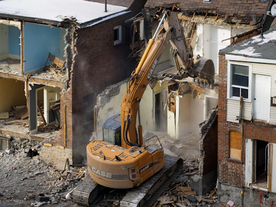 A bulldozer digging through the rubble of a building