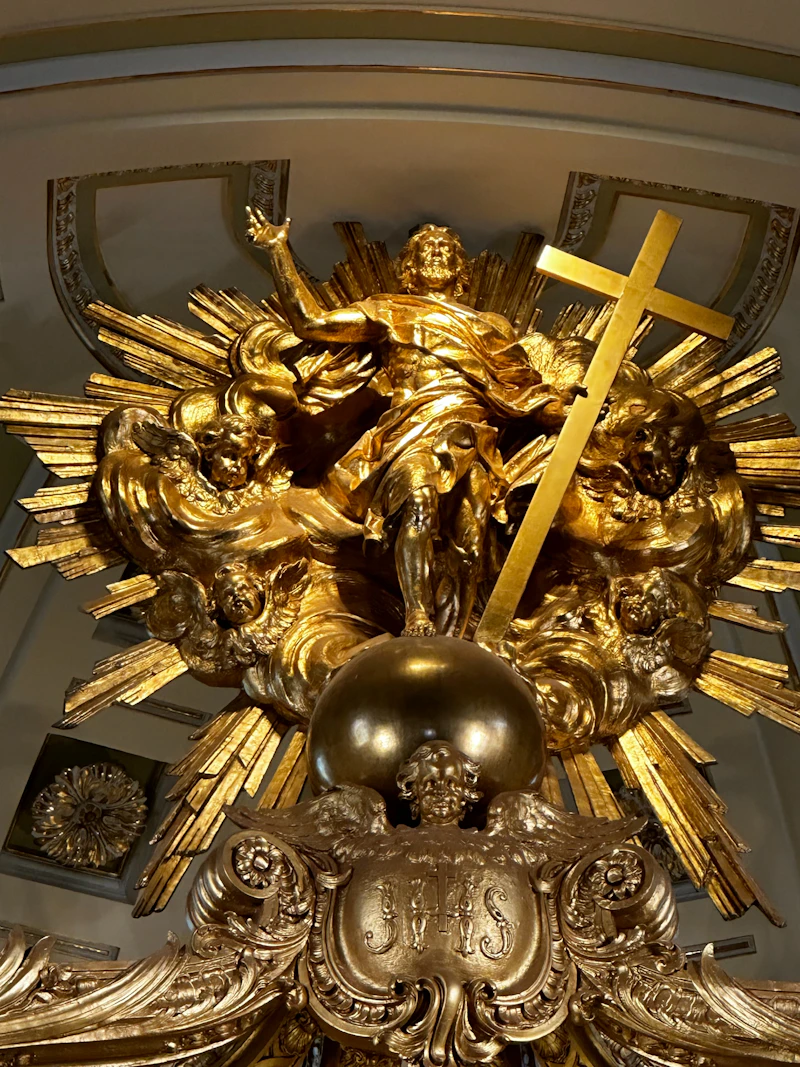 A gilded sculpture with a cross and sunburst inside a church
