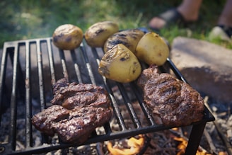 Steaks and potatoes are cooking on a grill