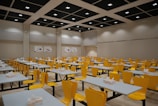 A room filled with lots of tables and yellow chairs
