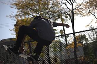 A man riding a skateboard up the side of a metal fence