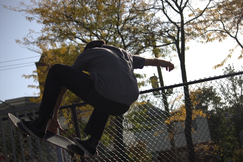 A man riding a skateboard up the side of a metal fence