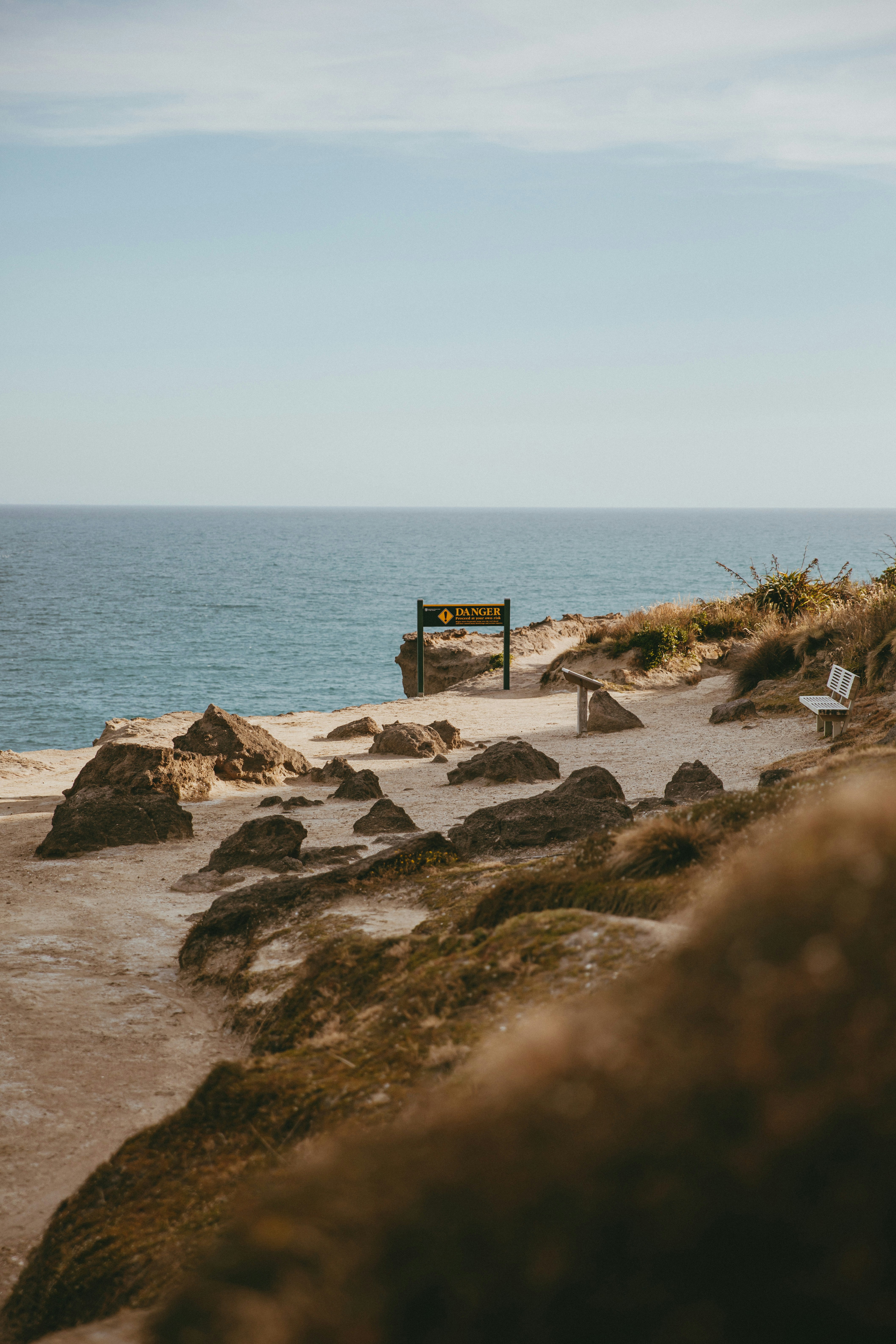 A bench sitting on top of a sandy beach next to the ocean