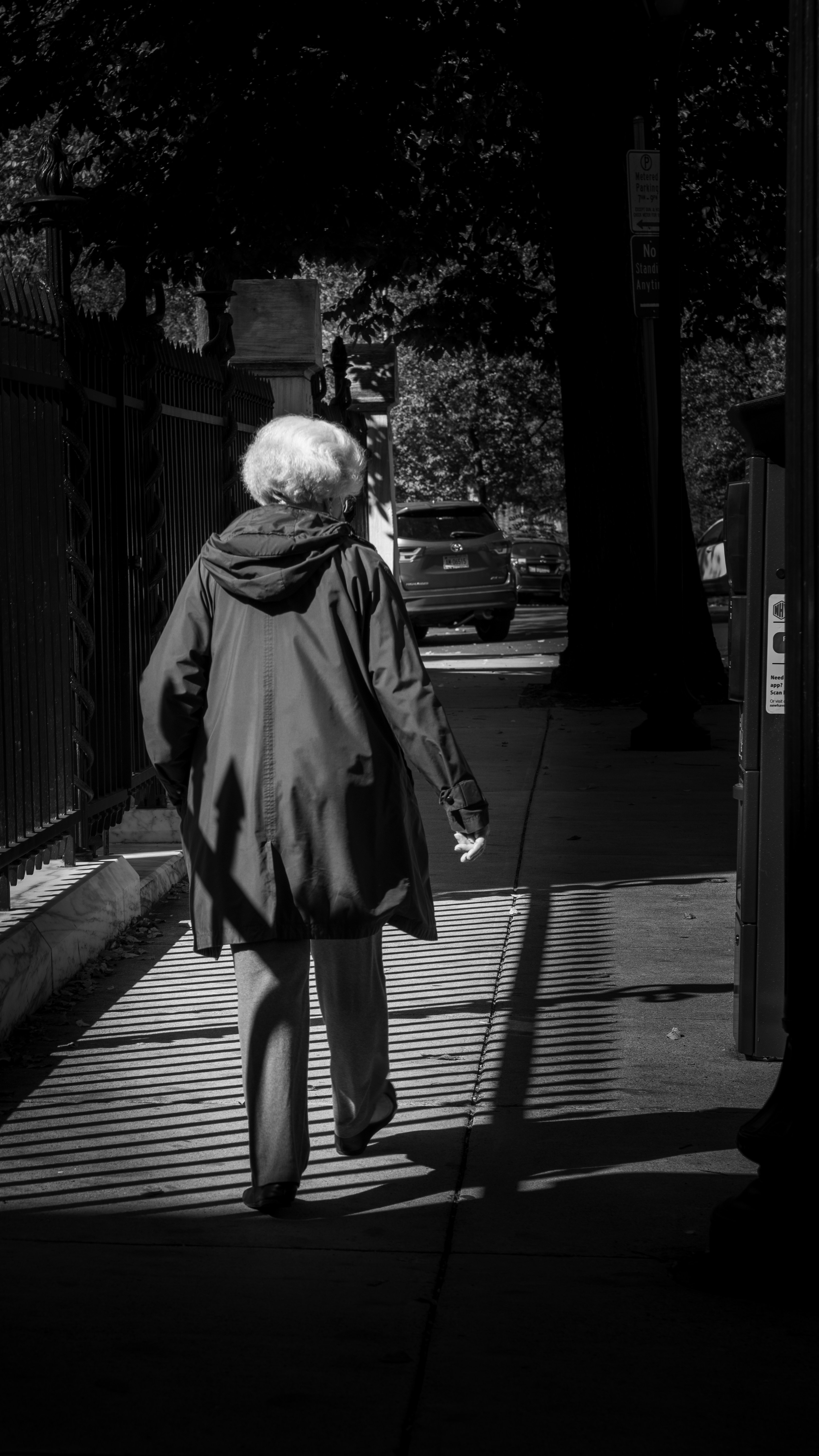 Eine Frau, die neben einem Zaun einen Bürgersteig entlanggeht