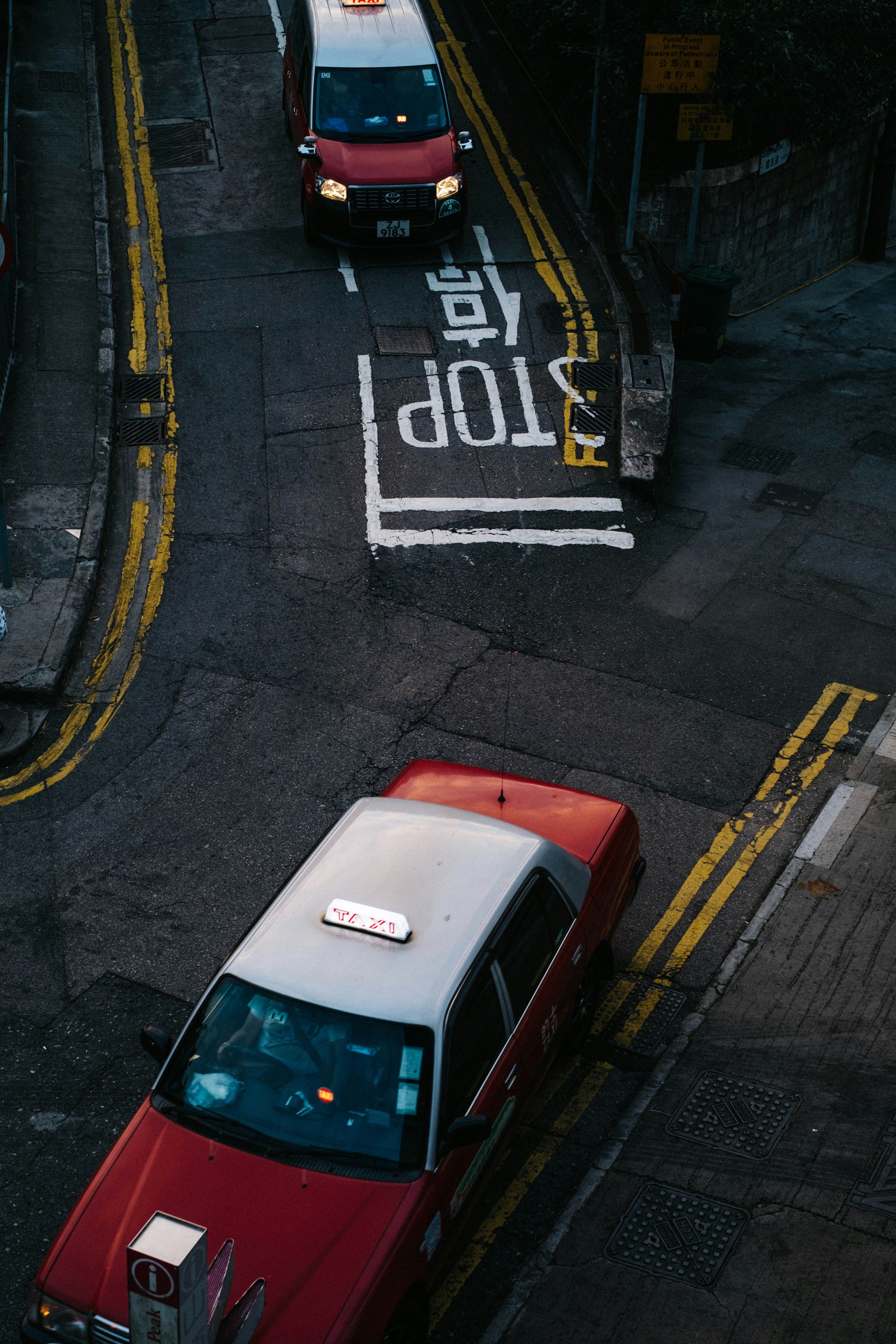 A red car driving down a street next to a white van