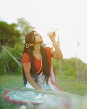 A woman in a red and white dress sitting in a field