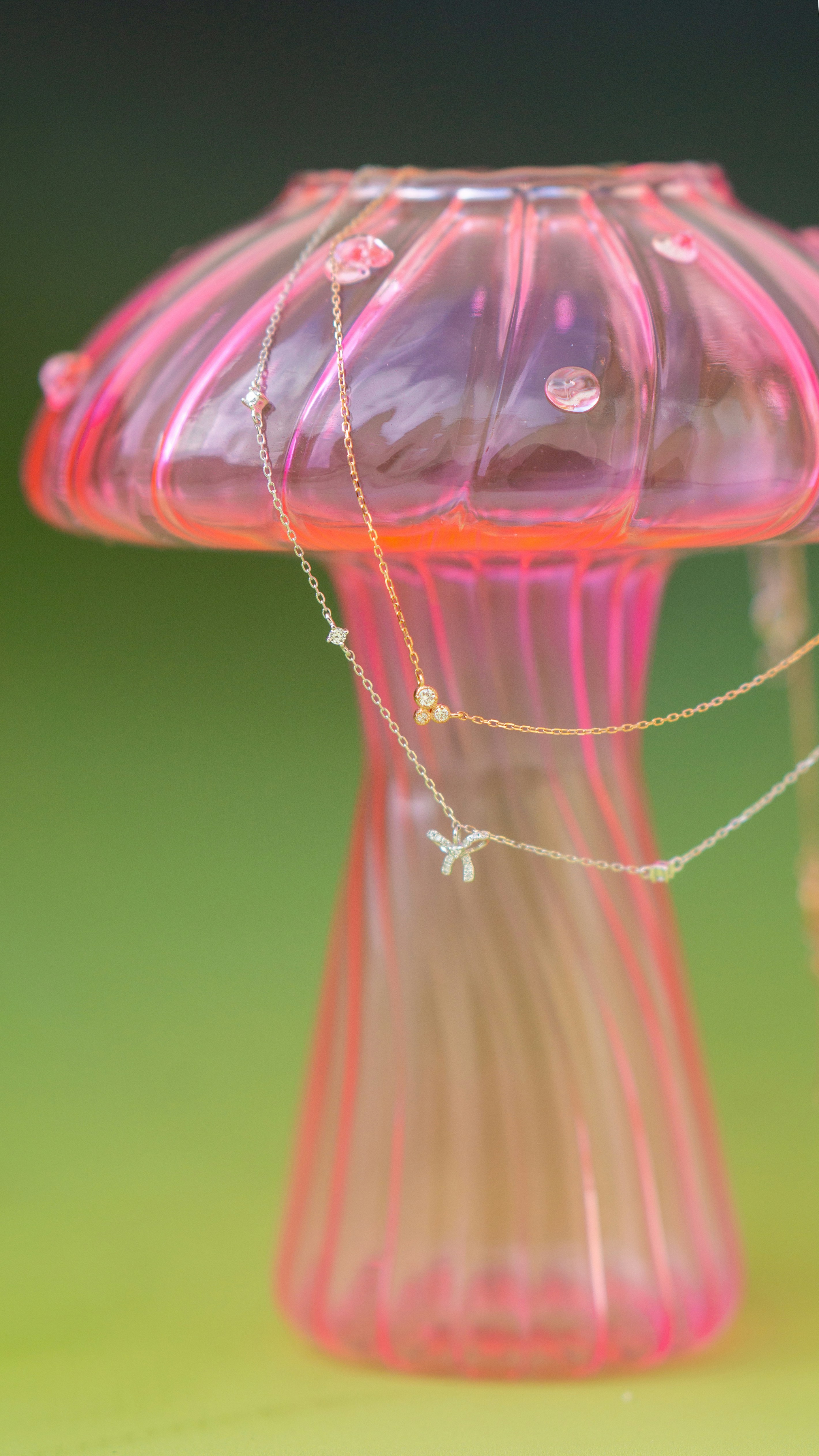 A pink glass object with a chain on it